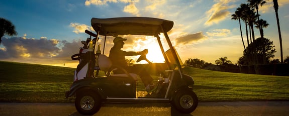 Senior driving a golf cart in the sunset