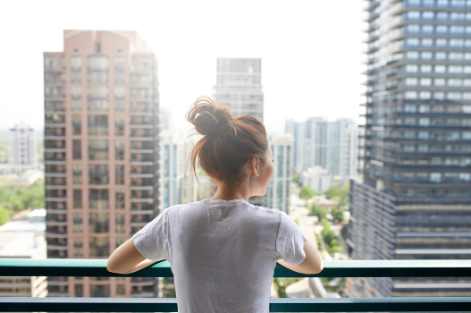 Woman enjoys the view from her high-rise condo balcony Woman enjoys the view from her high-rise condo balcony