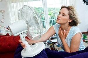 woman cooling herself with fan