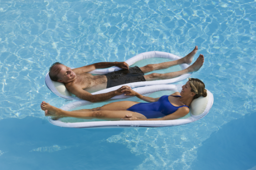3.1 HOAS - A couple holding hands and floating in a pool 3.1 HOAS - A couple holding hands and floating in a pool